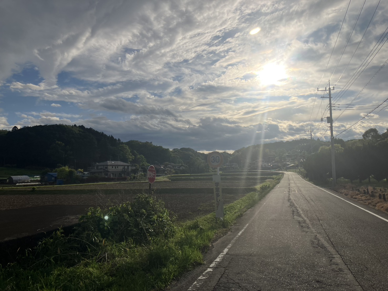 夕陽さす里道と「学童多し」の速度標識