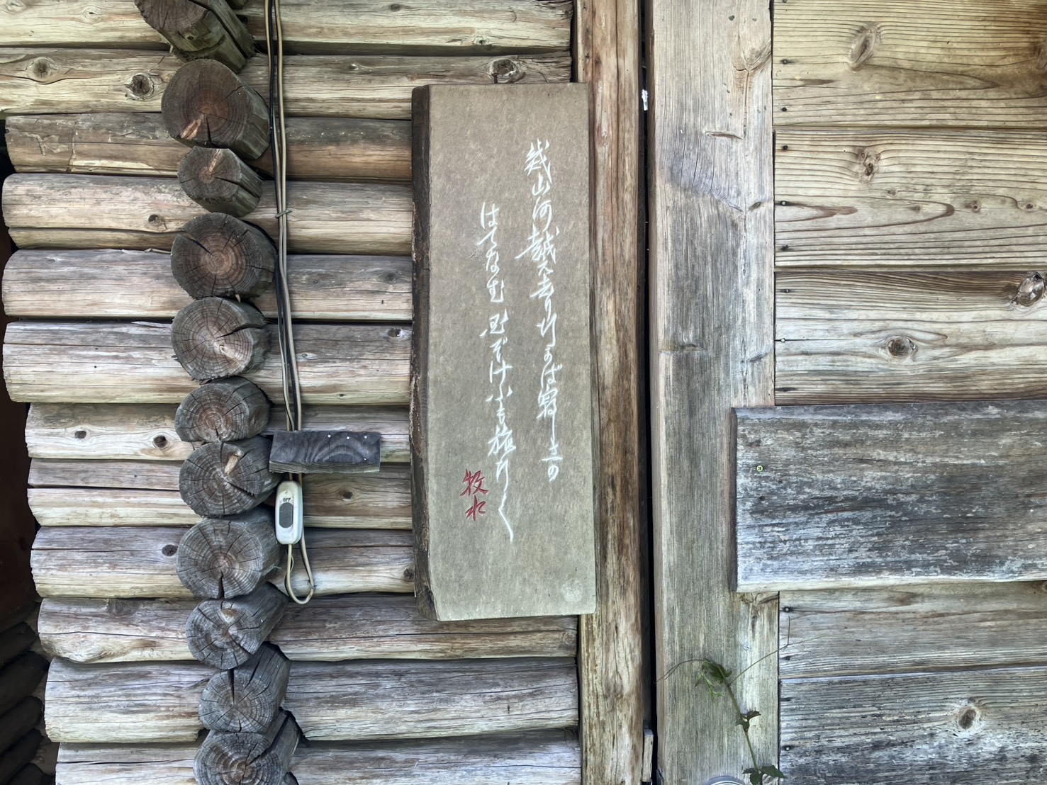 霜里農場の古い丸太小屋に掛けられた歌碑