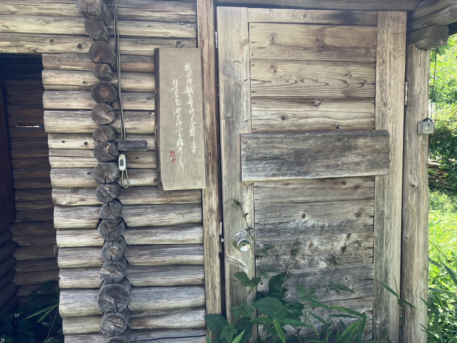 緑に包まれた霜里農場の丸太小屋の入口